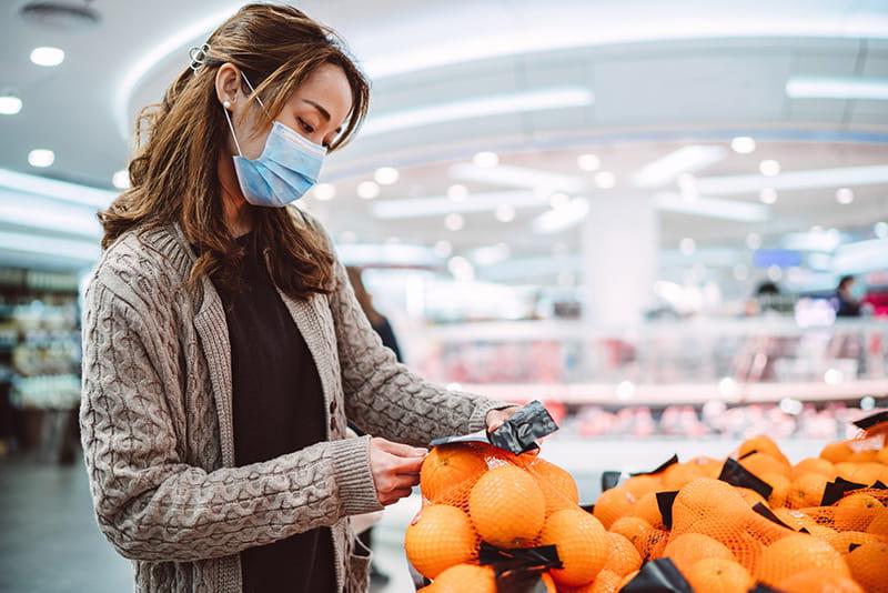 戴着面具在杂货店购物的女人